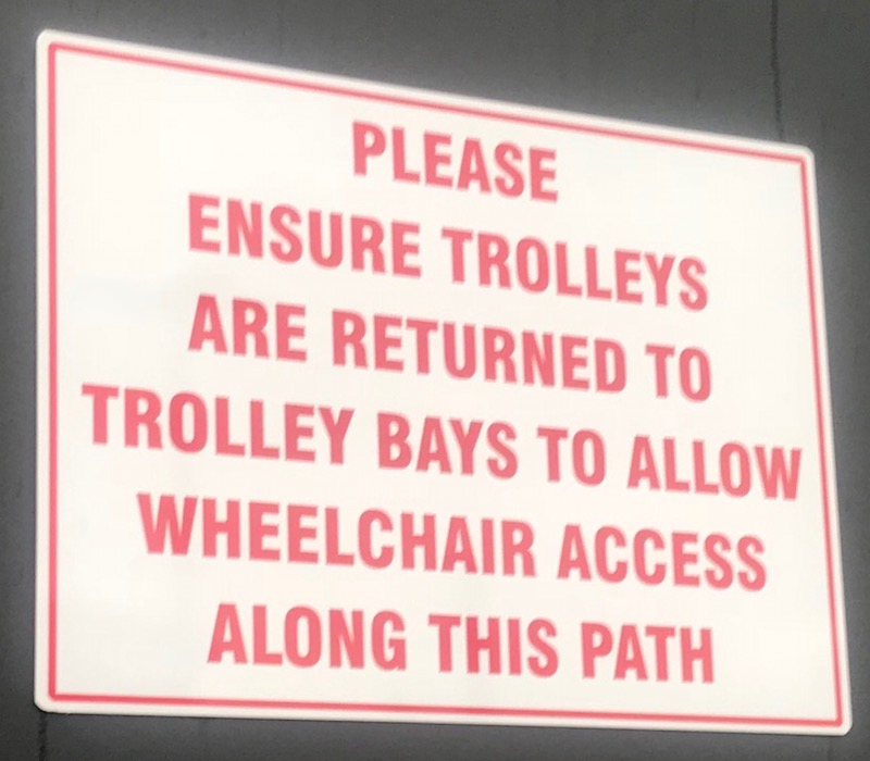 the sign reads 'please ensure trolleys are returned to trolley bays to allow wheelchair access along this path