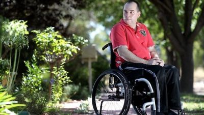 wheelchair john duthie - john sitting outside his house looking over his shoulder
