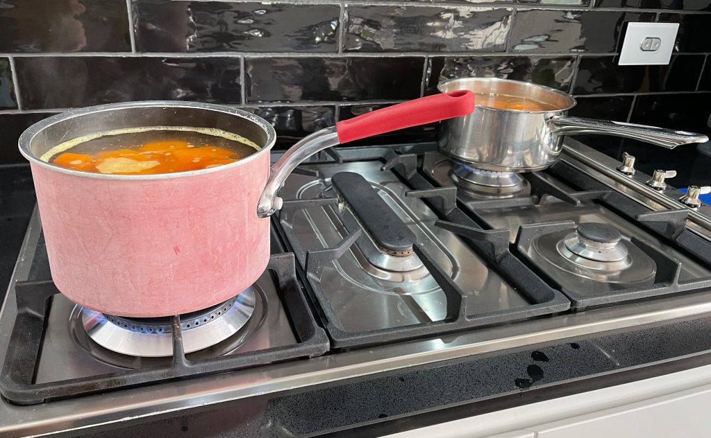 2 pots on a gas stove are boiling water, and the carrots are being cooked. freezing carrots cooking