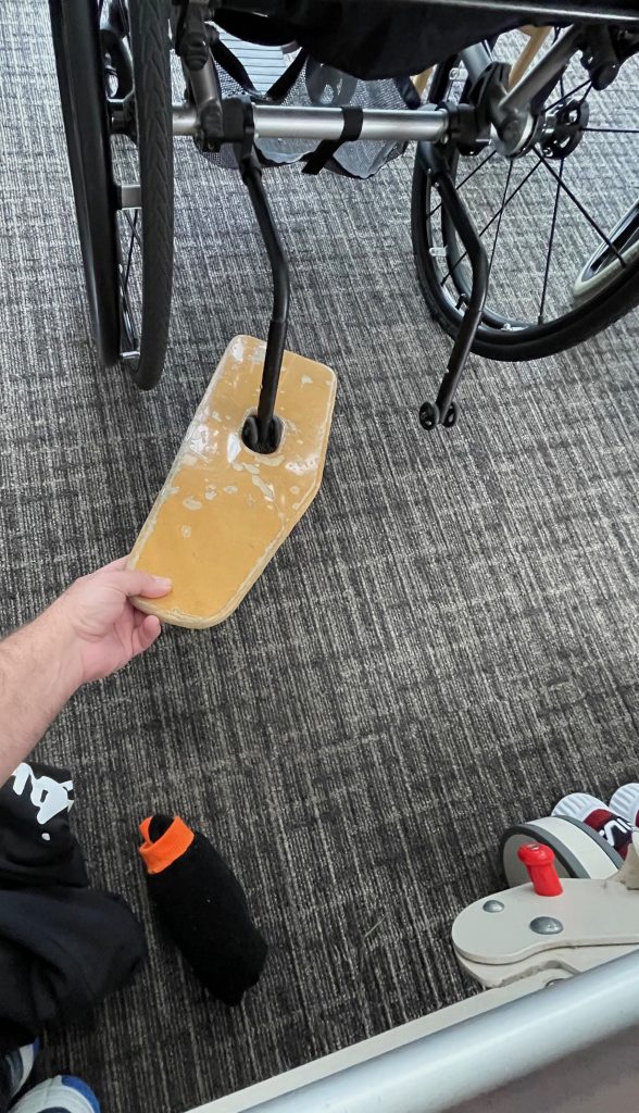 the manual chair has two little wheels at the back to prevent tipping, I hold my slider board, that has a hole, and I hook onto the chair