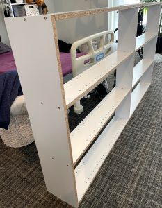 the bookshelf is against the bed