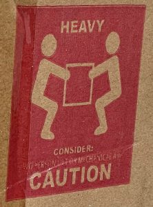 two men on a red background holding a heavy object - Building furniture from a wheelchair