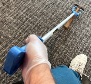 blue pickup stick is held and about to pick up a hammer