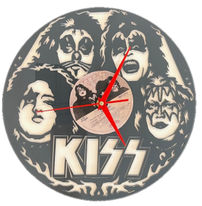 This image shows a circular wall clock inspired by the rock band KISS. The clock face features the black-and-white, laser-cut faces of the band members in their iconic makeup. The KISS logo is prominently displayed at the bottom, and the center holds a real vinyl record with visible text and a small photo of the band. Bright red clock hands contrast the monochromatic design, making this a striking homage to the legendary rock group.